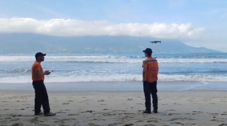 Buscas por Bruno Barreto Otsu em São Sebastião contam com drones, helicóptero Águia e apoio do GBMar A Defesa Civil de São Sebastião reforçou as buscas por Bruno Barreto Otsu, de 21 anos, desaparecido desde a última segunda-feira (11) após entrar no mar na costeira da praia de Toque-Toque Grande, na Costa Sul do município. A operação passou a contar com drones para monitoramento aéreo em áreas de difícil acesso. Para ampliar a área de monitoramento, a Defesa Civil passou a utilizar drones durante a operação. O equipamento permite alcançar pontos de difícil acesso, principalmente em locais atingidos por fortes ondas e mar agitado, onde a aproximação por terra ou embarcações é limitada. Segundo a Defesa Civil, a tecnologia auxilia no aumento do campo de visão das equipes e possibilita uma cobertura mais ampla da área marítima. O coordenador municipal da Defesa Civil, Ricardo Cardoso dos Santos, afirmou que o trabalho ocorre de forma integrada com outras forças de segurança e resgate da região. “Temos equipes preparadas, equipamentos e embarcações que podem contribuir nas buscas tanto pelo mar quanto nas costeiras. Estamos empenhados em apoiar todas as frentes da operação e esperamos que em breve possamos ter alguma notícia sobre o jovem”, declarou. Além das equipes terrestres e marítimas, a Polícia Militar também utiliza o Helicóptero Águia nas buscas aéreas pela região. De acordo com informações apuradas pelas equipes de resgate, Bruno entrou no mar para tentar salvar Maria Eduarda, também de 21 anos, após a jovem ser arrastada por uma onda enquanto caminhava pela costeira de Toque-Toque Grande. Maria Eduarda foi levada pela correnteza e encontrada cerca de cinco horas depois nas proximidades da praia de Barequeçaba, a aproximadamente cinco quilômetros do local inicial. Ela foi resgatada por um pescador que seguia em direção a Santos e acionou o Corpo de Bombeiros. Segundo relato prestado pela jovem aos bombeiros marítimos, Bruno não foi atingido diretamente pela onda, mas entrou na água na tentativa de ajudá-la e desapareceu em seguida. Familiares de Bruno Barreto Otsu também mobilizam campanhas nas redes sociais em busca de apoio voluntário para auxiliar nas buscas. Os pedidos envolvem proprietários de embarcações, mergulhadores e operadores de drones.