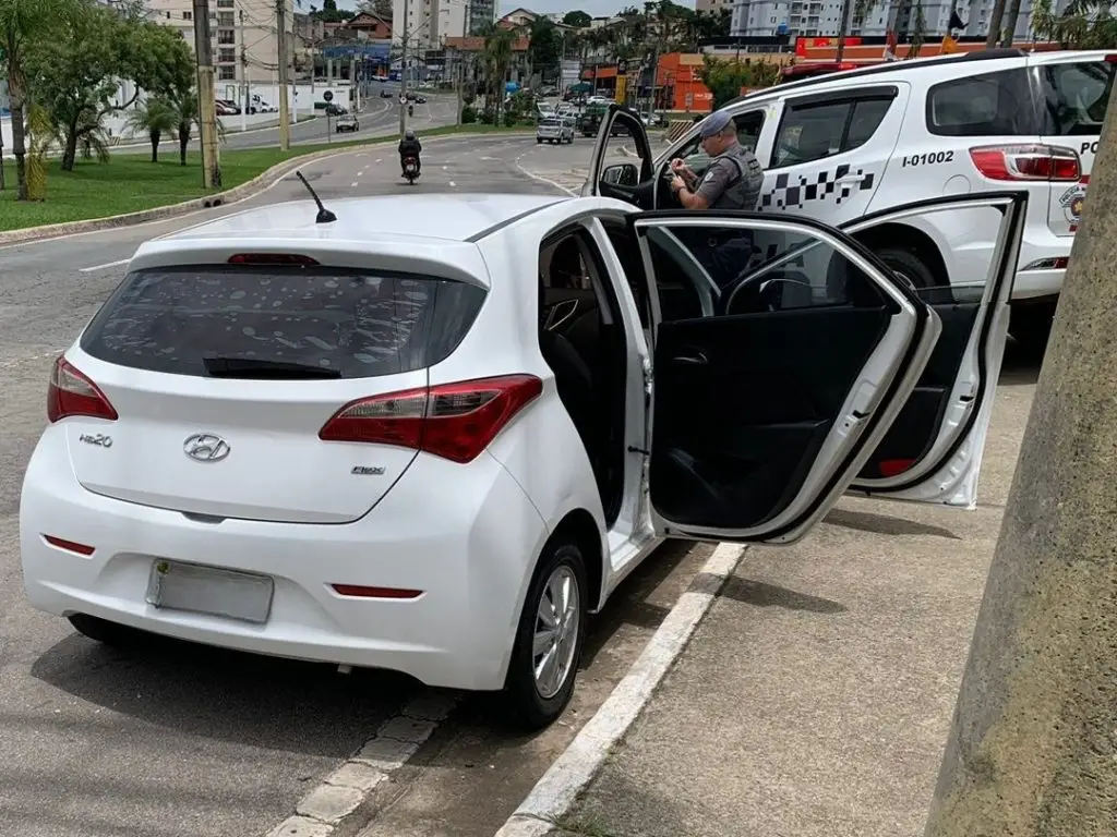 Homem é preso em São José dos Campos por adulteração de placa com fita isolante; crime foi identificado por câmeras do CSI Um homem foi preso por adulteração de placa na manhã da última segunda-feira (10), em São José dos Campos. A ação foi realizada por policiais militares do 1º Batalhão de Polícia Militar do Interior (1º BPM/I), após informações repassadas pelo Centro de Segurança e Inteligência (CSI) sobre um veículo branco com placas adulteradas circulando pela avenida Presidente Juscelino Kubitschek. Durante o patrulhamento, a equipe localizou o automóvel em frente a um supermercado e realizou a abordagem. Na vistoria, os policiais constataram que o condutor havia usado fita isolante para alterar a numeração da placa, que originalmente correspondia a um carro da mesma marca e modelo, mas de cor preta e registrado em outra cidade. Ocorrência